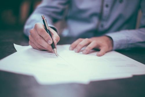 Man writing with pen and paper 